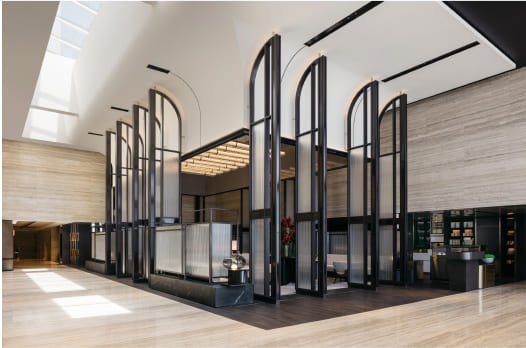 Modern building interior with arched metallic structures surrounding a central reception desk under a high ceiling with natural light.
