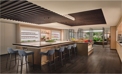 A modern kitchen with a large central island, bar stools, pendant lights above, and extensive cabinetry. The space appears clean and well-lit, with no people present.